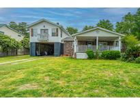 Charming two-story home with a well-maintained lawn and a covered front porch perfect for relaxing at 312 Lake Moultrie Dr, Bonneau, SC 29431