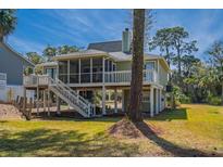 Beautiful exterior view of raised house featuring a screened porch and lush landscaping at 60 Rice Ln, Edisto Beach, SC 29438