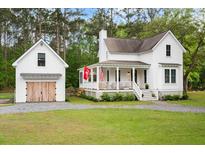 Charming two-story white home with a detached garage and a welcoming front porch at 6373 Farm House Rd, Ravenel, SC 29470