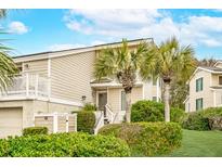 Charming coastal home featuring lush landscaping, palm trees, and a welcoming entryway at 9 Fairway Dunes Ln, Isle of Palms, SC 29451