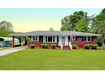Charming brick home featuring mature landscaping, covered carport, and classic architectural details at 104 Bryant St, Saint George, SC 29477