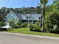 Charming home featuring a manicured lawn, lush landscaping and inviting front porch at 1207 Rivers Reach Dr, Wando, SC 29492