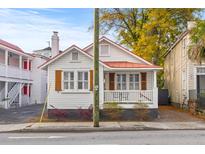 Quaint home featuring a red roof, shuttered windows, and inviting front porch amidst vibrant foliage at 177 Spring St, Charleston, SC 29403