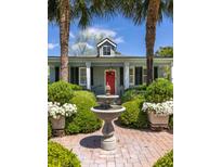 Charming home featuring a red front door, well-manicured garden, and a lovely water fountain at 2050 Wappoo Hall Rd, Charleston, SC 29412