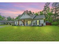 Charming single-story home featuring a covered porch with rocking chairs and lush green lawn at 229 Twin Lake Dr, Summerville, SC 29483