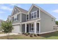 Charming two-story home featuring a well-maintained lawn, gray siding, and a two-car garage at 319 Abercom Place Dr, Moncks Corner, SC 29461