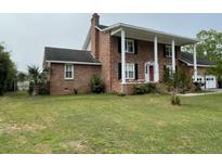 Beautiful brick home featuring a front porch with stately white columns and a well-manicured lawn at 36 Forde Row, Charleston, SC 29412