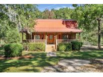 Charming log cabin with a covered porch and neatly manicured landscaping at 398 W Fisher Rd, Summerville, SC 29483