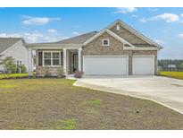 Charming brick home featuring a two-car garage and well-manicured front yard at 431 Canal Crossing Way, Huger, SC 29450