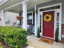 Charming covered front porch with rocking chairs and a vibrant red door with decorative wreath at 435 Foxbank Plantation Blvd Blvd, Moncks Corner, SC 29461