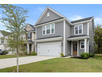 Charming two-story home with a well-manicured lawn and a two-car garage with gray wood-look siding at 8654 Windsor Hill Blvd, North Charleston, SC 29420