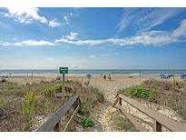 Scenic beach access to the ocean with volleyball and seating under a partly cloudy sky at 1004 Ocean Blvd # 108, Isle of Palms, SC 29451