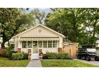 Charming single-story home with manicured lawn, quaint awning, and adjacent parking with golf cart at 116 Magnolia Ave, Charleston, SC 29403