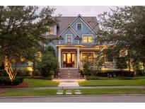 Charming two-story blue home with inviting front porch, manicured lawn, and mature trees at 187 Ithecaw Creek St, Daniel Island, SC 29492