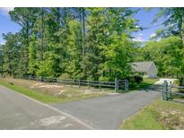 Gated driveway leading to a single-story house surrounded by lush trees at 209 Cheyenne Rd, Summerville, SC 29483