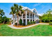 Stunning two-story home featuring double porches, a lush lawn, and attractive landscaping at 2870 Ion Ave, Sullivans Island, SC 29482