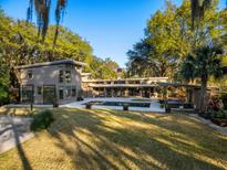 Secluded backyard features a pool, lush lawn, mature trees, and a modern house design at 317 Seewee Cir, Mount Pleasant, SC 29464