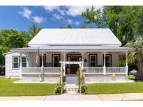 Charming two-story home featuring a metal roof, inviting porch, and manicured lawn, with American flag waving at 21785 Lowcountry Hwy, Ruffin, SC 29475