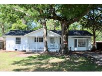 Charming white brick home featuring mature trees, a cozy front porch, and a freshly painted exterior at 227 Amy Dr, Goose Creek, SC 29445