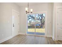 Bright dining area features a sliding glass door to the backyard and modern light fixture at 2606 Bennett Yard Rd, North Charleston, SC 29405