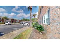 Exterior view of a brick apartment building with ample parking spaces and partial tree coverage at 415 Parkdale Dr # 2F, Charleston, SC 29414
