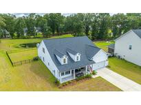 Charming home with a well-manicured lawn, a pond, and an inviting covered front porch at 7070 Pumpkinseed Dr, Johns Island, SC 29455
