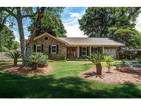 Charming brick home with a well-manicured lawn, mature trees, and inviting front porch at 1006 Ibis Ct, Mount Pleasant, SC 29464
