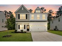 Charming two-story home with neutral siding, manicured lawn, and attached two car garage at 296 Torslanda Ln, Summerville, SC 29486