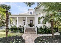 Inviting two-story home features a charming front porch, beautiful landscaping, and a brick walkway leading to the front door at 300 Ginned Cotton St, Charleston, SC 29492