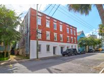 Three-story brick building with white trim and several windows, street view with parked cars at 35 Society St # D, Charleston, SC 29401