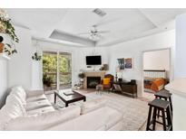 Bright living room with a white couch, fireplace, ceiling fan, and sliding glass doors to the balcony at 60 Fenwick # 936, Johns Island, SC 29455