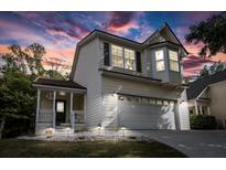 Charming two-story home with a well-manicured lawn, a covered porch, and an attached two-car garage with exterior lighting at 675 Fair Spring Dr, Charleston, SC 29414