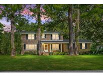 Charming two-story brick home featuring a covered front porch and a lush green lawn with mature trees at 710 S Magnolia St, Summerville, SC 29483