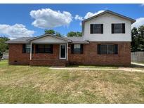 Two-story home featuring a classic brick exterior and a well-maintained lawn under a partly cloudy blue sky at 1110 Pickett St, Moncks Corner, SC 29461