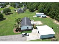 A charming single-Gathering home with spacious yard and large detached garage, surrounded by lush greenery and mature trees at 131 Travis Hill Rd, Moncks Corner, SC 29461