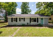 Charming one-story home with a teal door and black shutters, surrounded by lush trees at 2219 Eagle Dr, North Charleston, SC 29406