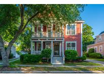 Charming two-story home features a double porch, lush landscaping, and a well-manicured front yard at 2324 High Tide Dr, Charleston, SC 29414