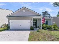 Charming single-story home with a two-car garage, well-manicured lawn and an American flag at 2809 Conservancy Ln, Charleston, SC 29414