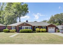 Charming brick home with well-maintained landscaping, a driveway, and an attached garage at 5029 Victoria Ave, North Charleston, SC 29405