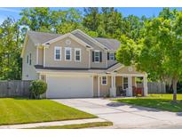 Charming two-story home with a well-maintained lawn, inviting front porch, and two-car garage at 606 Knowledge Dr, Ladson, SC 29456
