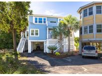 Charming coastal home with a light blue exterior, palm trees, and a covered parking area underneath at 73 Fairway Dunes Ln, Isle of Palms, SC 29451
