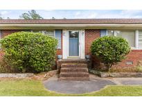 Charming brick home featuring a lovely blue door and manicured bushes and brick steps at 9995 Lodge Hwy, Lodge, SC 29082