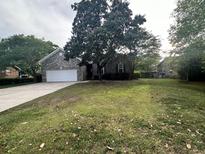 Charming single-story brick home with a lush front yard and mature trees, creating an inviting curb appeal at 104 Winston Way, Goose Creek, SC 29445