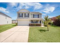 Charming two-story home with a well-manicured lawn, attached garage, and inviting front porch, perfect for suburban living at 1130 Moss Grove Dr, Moncks Corner, SC 29461