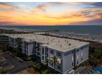 Coastal condo aerial view showcases beachfront access, balcony views, and vibrant sunset skies on a well-populated beach at 1140 Ocean Blvd # 201, Isle of Palms, SC 29451