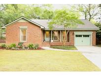 Charming brick home with a well-manicured lawn, complemented by a lovely tree and matching garage and door accents at 1228 Penny Cir, Mount Pleasant, SC 29464