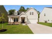 Charming home with a well-manicured lawn, stone accents, and a welcoming covered porch at 1730 Refuge Dr, Ladson, SC 29456