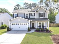 Two-story home boasts gray siding, dark shutters, a well-manicured lawn, and a two-car garage at 2016 Elvington Rd, Johns Island, SC 29455