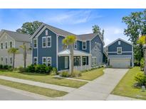 Charming two-story home boasts a stylish blue exterior, attached garage and well-manicured lawn at 2557 Hatch Dr, Johns Island, SC 29455