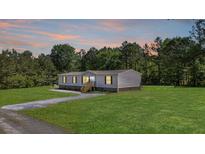 Charming single-story home with well-manicured lawn, gray siding, and surrounded by lush trees at sunset at 314 Hickory Nut Way, Cross, SC 29436